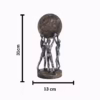 Decorative sculpture of three human figures lifting a textured globe, placed on a wooden table in a modern living room setting, symbolizing teamwork and unity.
